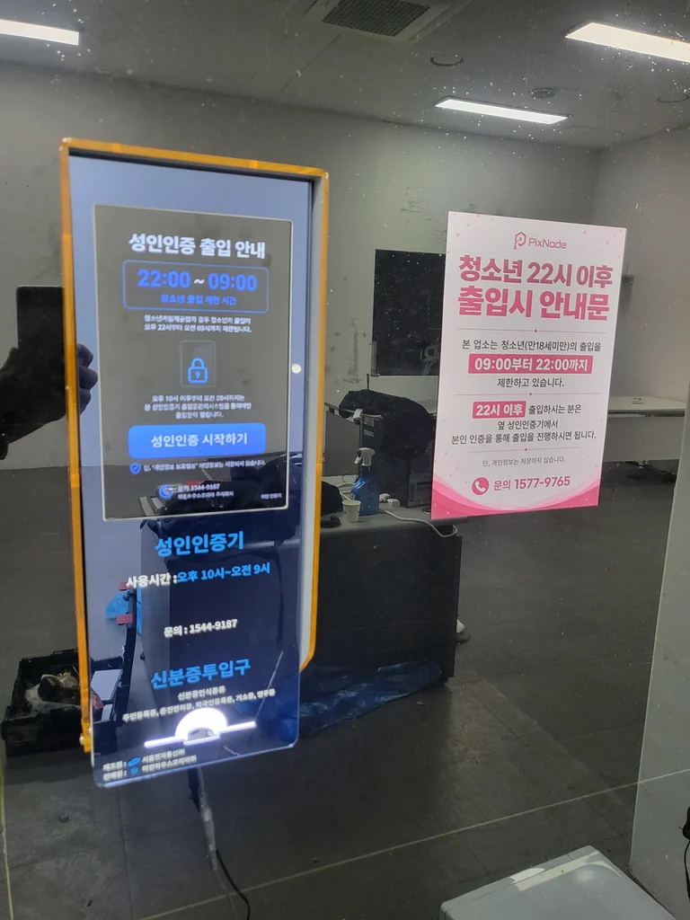 금색 본체의 성인인증기 정면과 성인인증 출입 안내 화면